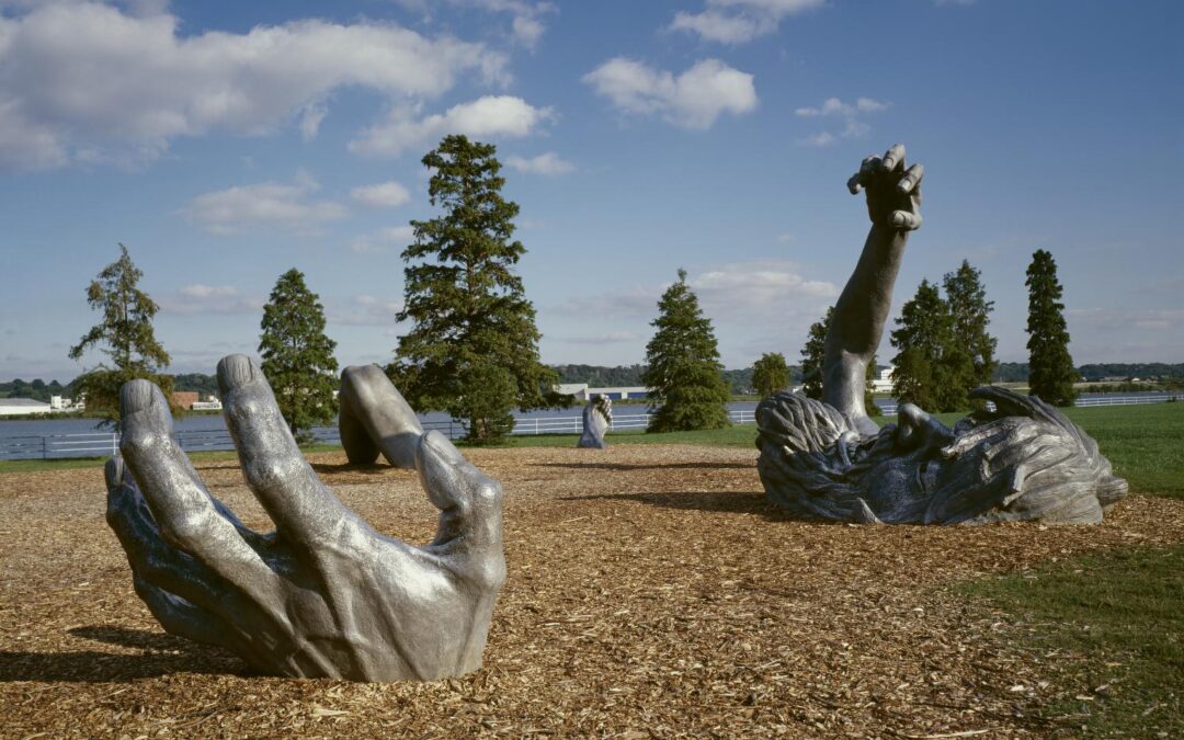 Giant sculpture of emerging hands and face.