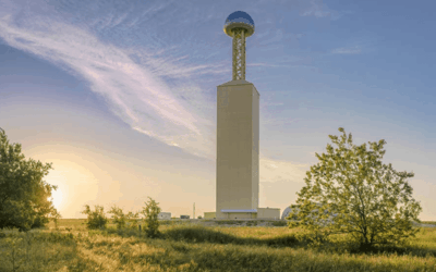 Tall tower in a grassy field landscape.