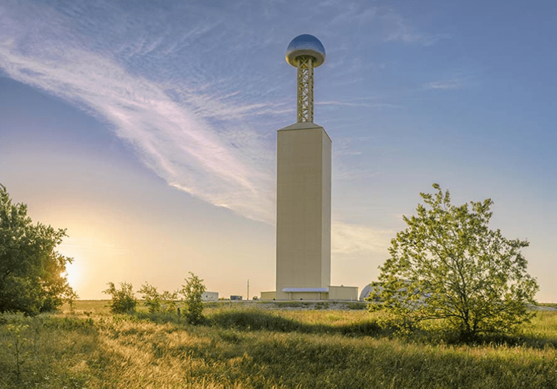Tall tower in a grassy field landscape.